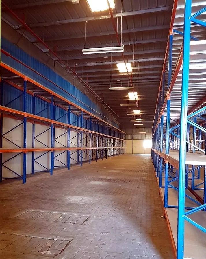 Pallet racking rows with orange beams and blue frames in an Umm Al Quwain warehouse
